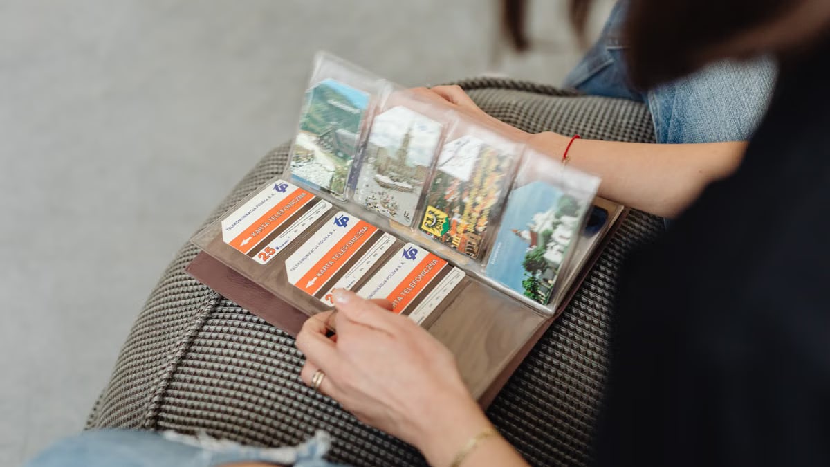 A person flipping through a vintage photo album filled with postcards.